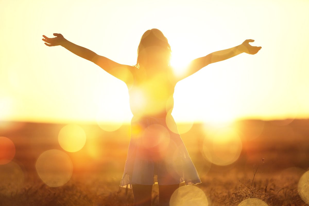 Young woman on field under sunset light
